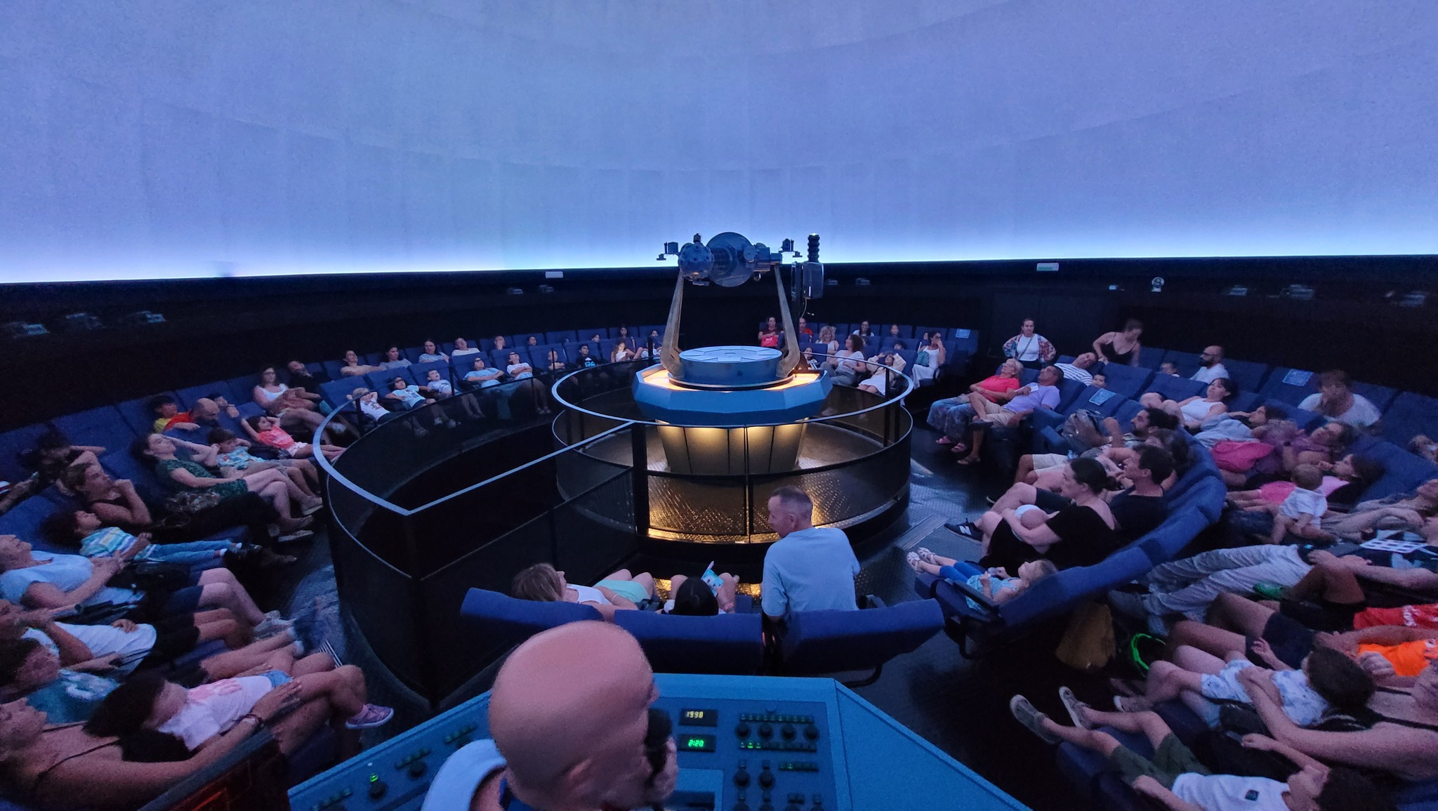 El público estaba sentado en un teatro circular con un escenario central y una gran pantalla curva en la parte superior.